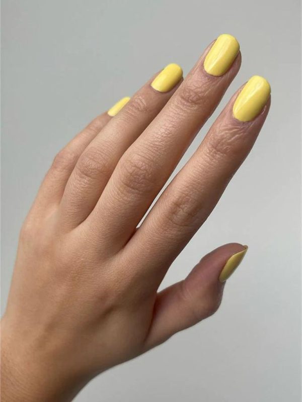Hand, gefärbt mit gelben Nagellack von der Marke Nailberry und der Farbe 
