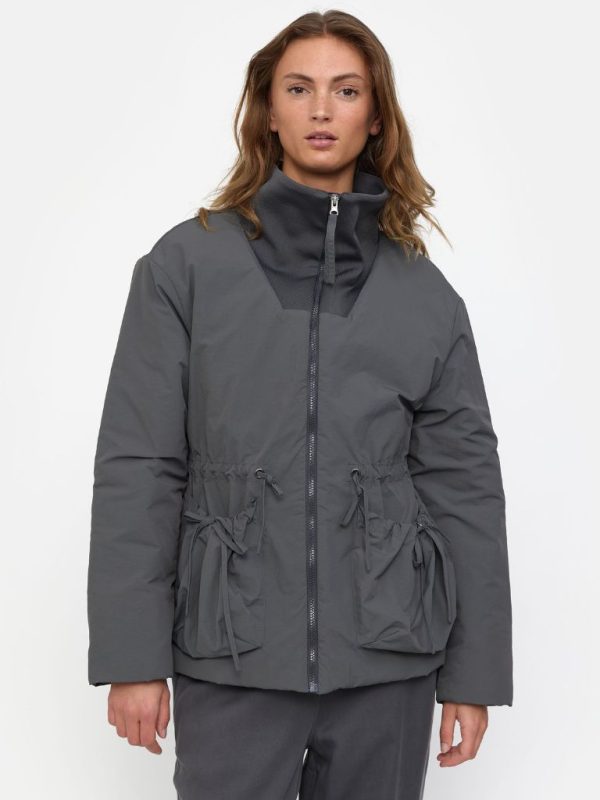 Modell trägt graue Jacke mit Seitentaschen, hohem Kragen, Reissverschluss in Dunkelgrau