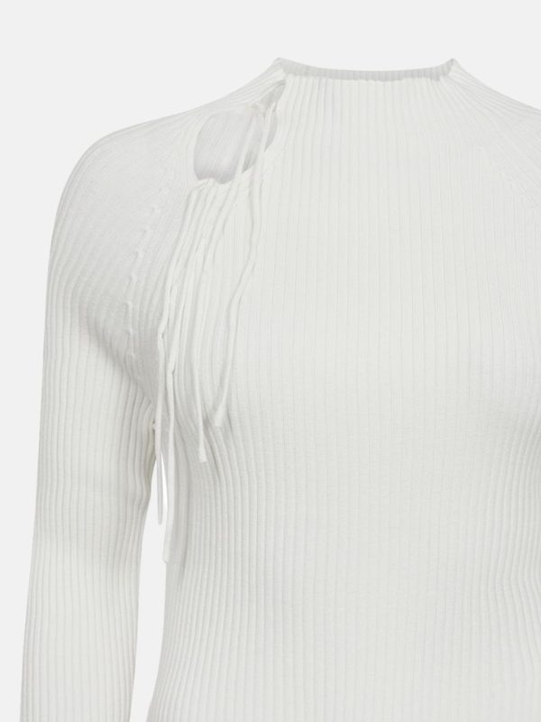 Gros plan sur un pull blanc en tissu côtelé avec un petit col montant et des fils décoratifs qui pendent sur le côté droit de l'épaule